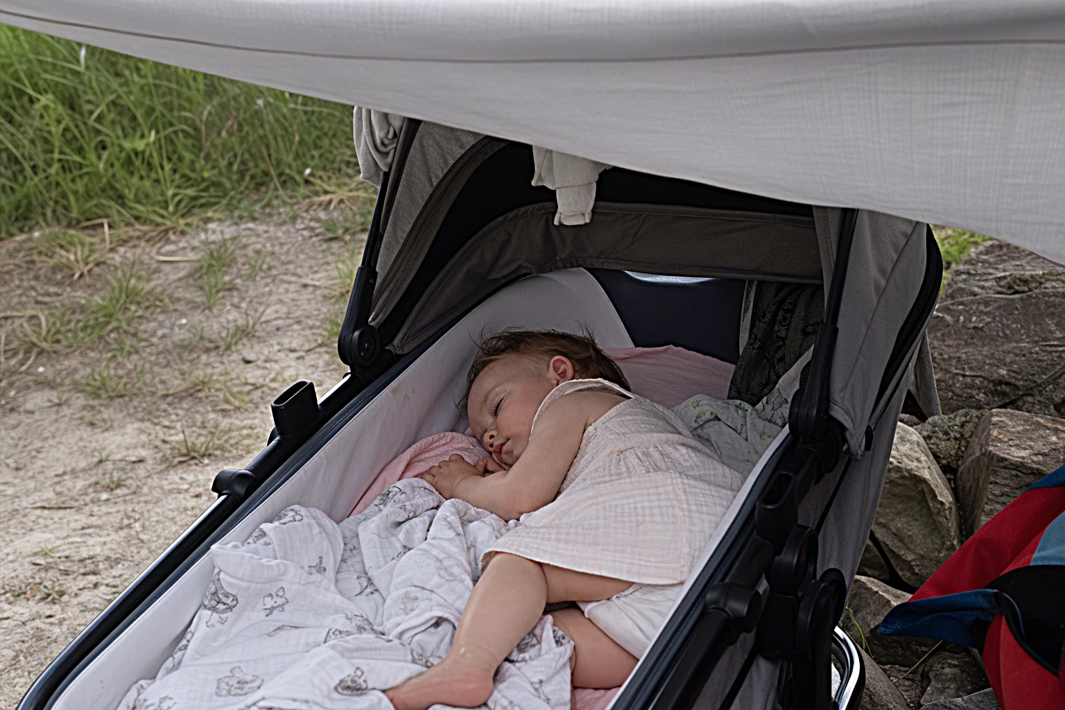 Ein Baby schläft friedlich im Schatten unter einem Sonnenschutz im Sommer, sanftes weiches Licht